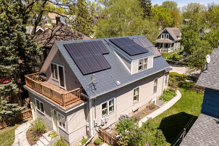 Deep Charcoal Interlock Slate aluminum roof on a cream coloured two-storey home with dormers among tall, Minneapolis, Minnesota