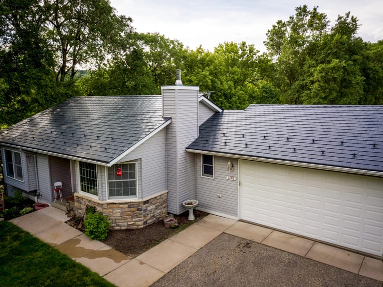 Deep Charcoal Interlock Slate aluminum roof on a ranch-style home with a metal roof among tall trees, Red Wing, Minnesota