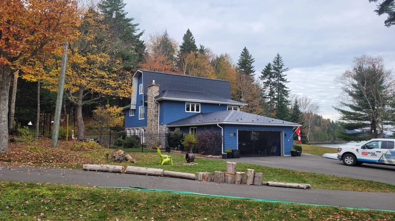Black Interlock Slate aluminum roof on a blue two-storey home with a black metal roof in a, Utopia, New Brunswick