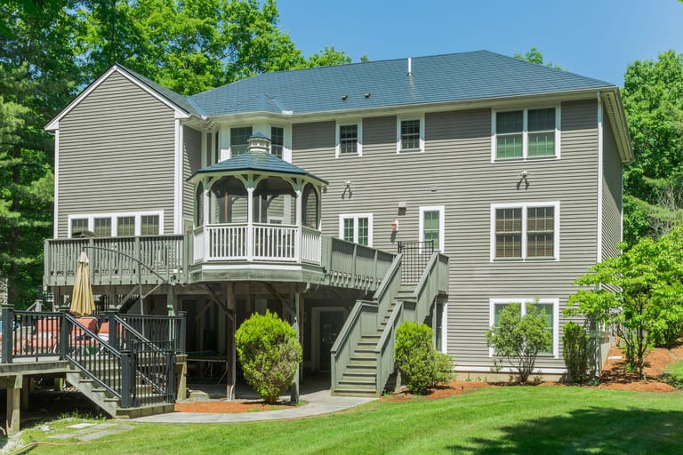 Rear elevation of a 2-story Colonial home in Salem, NH featuring Interlock black aluminum slate metal roofing with a multi-hip complex roof and built-in gazebo deck.