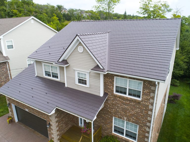 Aerial front-right view of a two-storey brick home in Dartmouth NS with Interlock Tudor Brown cedar shingle metal roofing, featuring a centre dormer and covered entry.