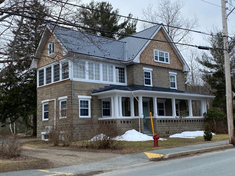 Deep Charcoal Interlock Slate aluminum roof on a brown two-storey home with dormers on a snow-covered, Mahone Bay, Nova Scotia