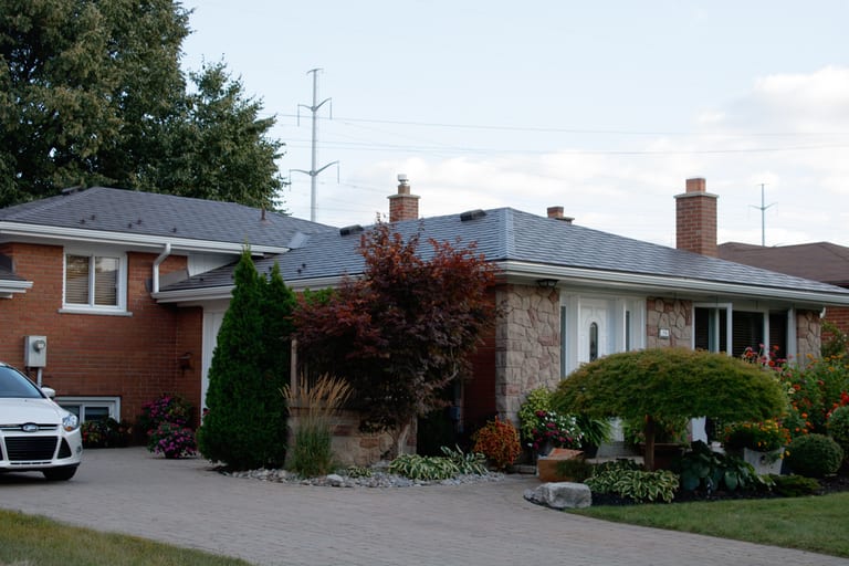 Single-storey ranch home in Scarborough with Interlock Tudor Brown aluminum slate metal roof, multiple chimneys, and well-landscaped front yard.