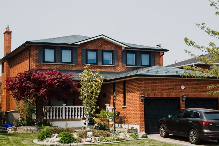 Two-storey brick Colonial home in Woodbridge ON with deep charcoal Interlock aluminum slate metal roofing on a multi-hip complex roof.
