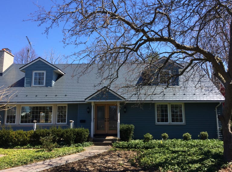 Cape Cod home with Interlock deep charcoal aluminum slate metal roof, twin dormers, snow guards, and blue siding in Niagara on the Lake.