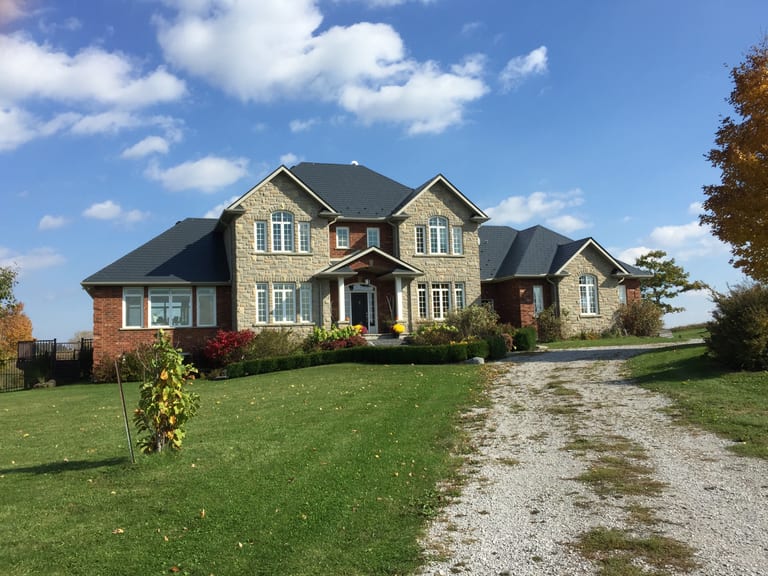 Large two-storey Colonial stone-and-brick home in rural Schomberg, ON, featuring a complex multi-hip Interlock aluminum slate roof in Deep Charcoal.