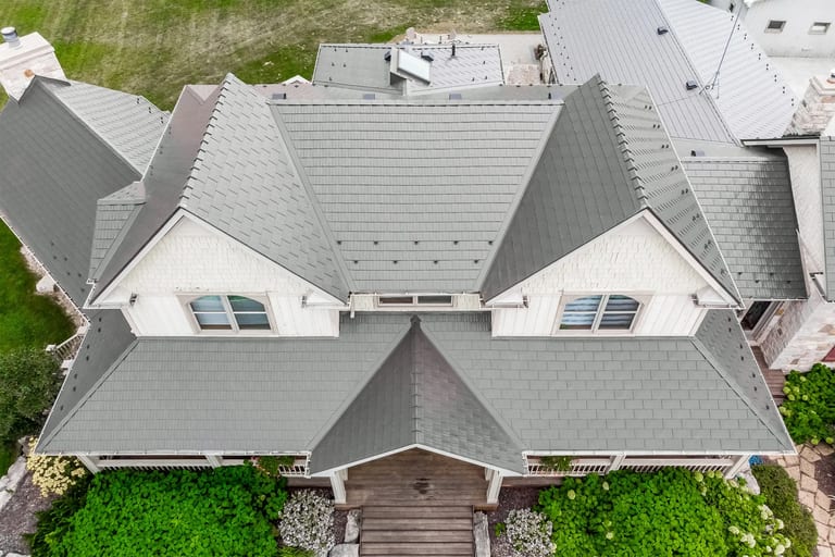 Aerial drone view of a complex multi-hip Interlock aluminum cedar shingle roof in Tudor Brown on a large Craftsman-style home in Pefferlaw, ON.
