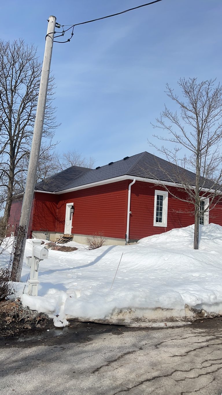 Single-storey red ranch home with Interlock Tudor Brown aluminum slate hip roof, surrounded by deep winter snow in Orillia, ON.