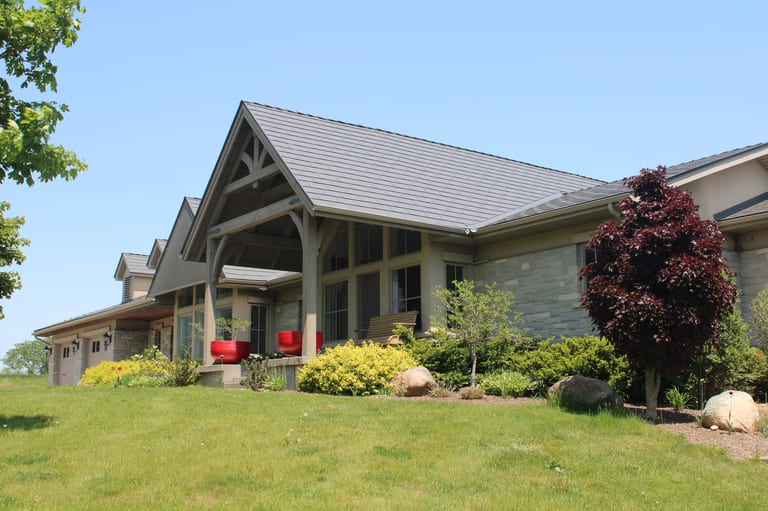 Musket Grey Interlock Cedar Shingle aluminum roof on a beige ranch with a metal roof surrounded by lush greenery, Guelph, Ontario