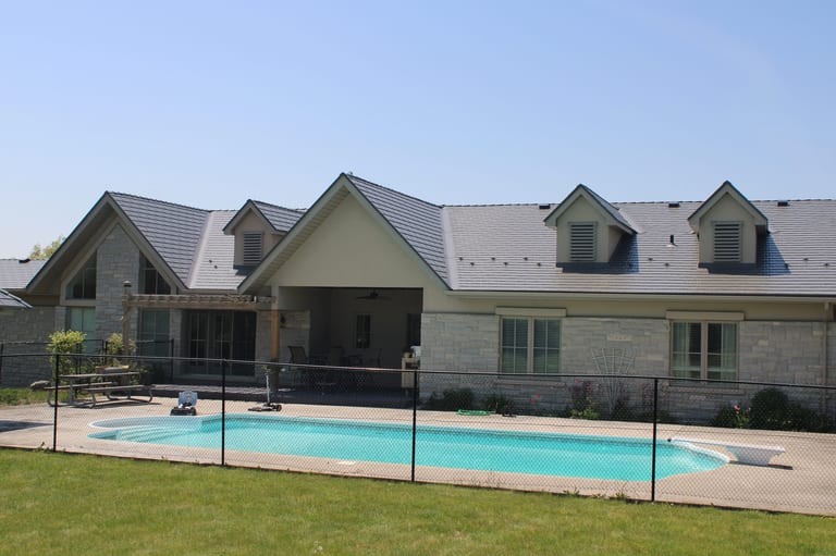 Musket Grey Interlock Cedar Shingle aluminum roof on a grey one-storey home with dormers and a pool in a rural, Guelph, Ontario