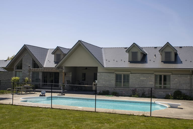 Rear elevation of a large Craftsman-style home in Guelph, ON featuring Interlock Musket Grey cedar shingle metal roofing with multiple dormers and louvered vents.