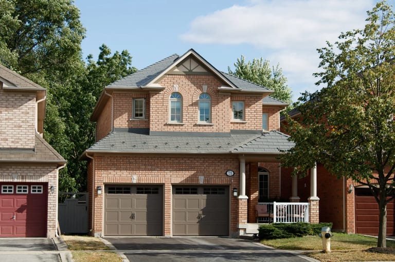 Black Interlock Cedar Shingle aluminum roof on a brown two-storey home with dormers among trees, Toronto, Ontario