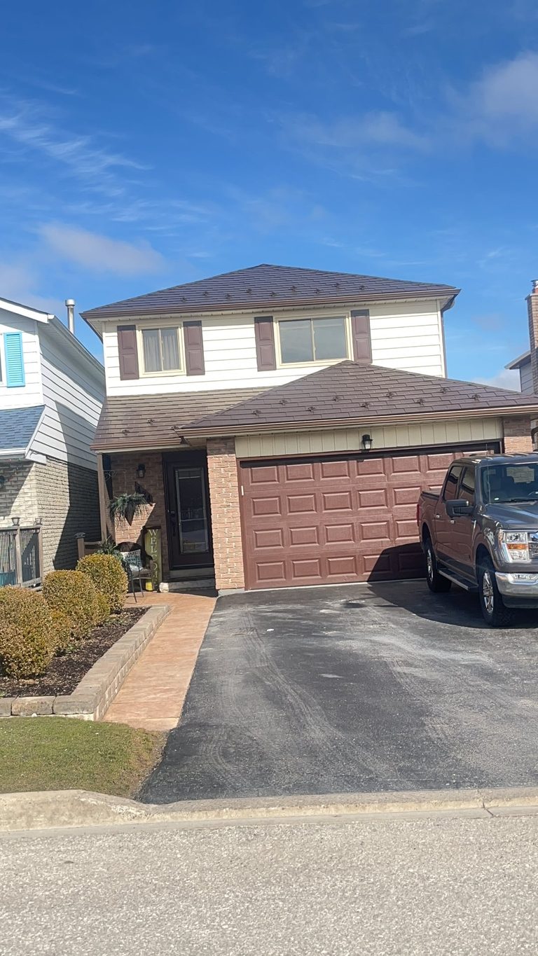 Two-storey suburban home in Bradford, ON with Interlock Colonial Brown aluminum slate metal roofing on a hip-style roof, paired with brick facade and brown garage door.