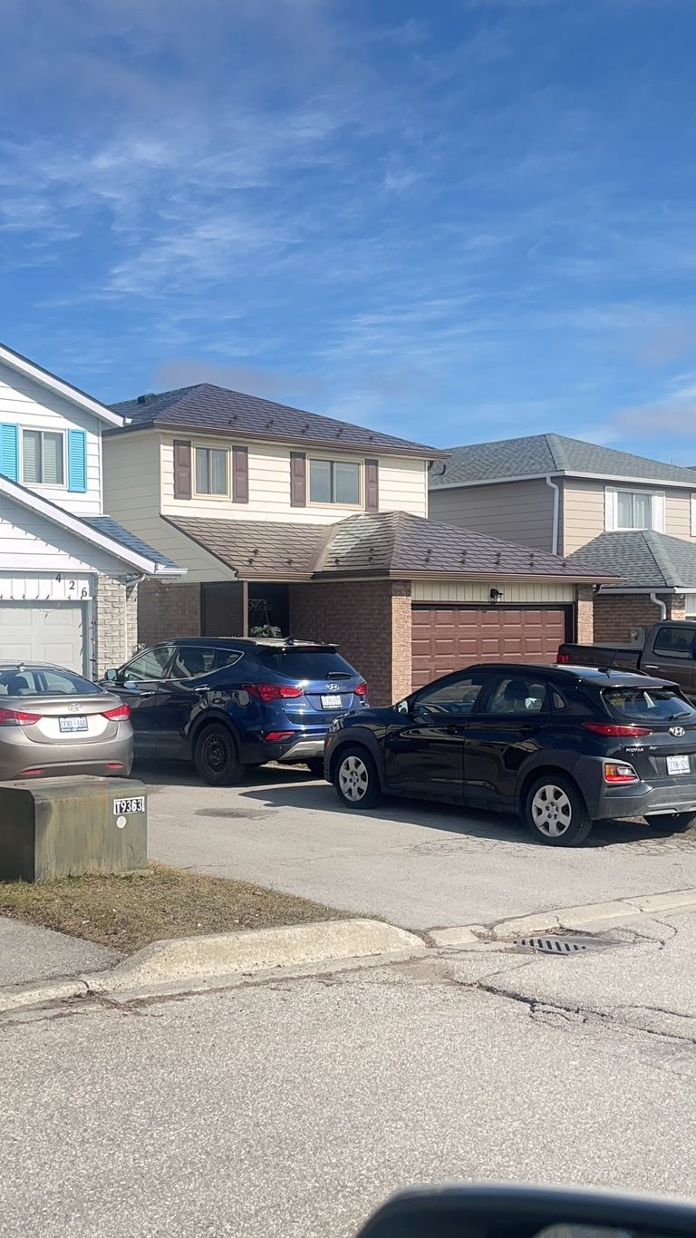 Two-storey suburban home in Bradford, ON with Interlock Colonial Brown aluminum slate metal roofing on a multi-hip roof, viewed from the street.
