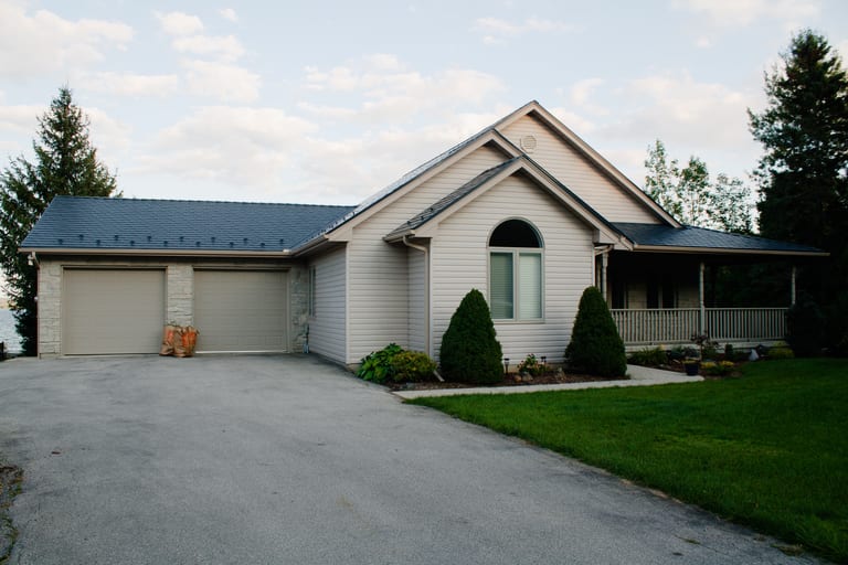 Single-family ranch home in Owen Sound ON with Interlock deep charcoal aluminum slate metal roofing, gable profile, attached two-car garage, and covered front porch.
