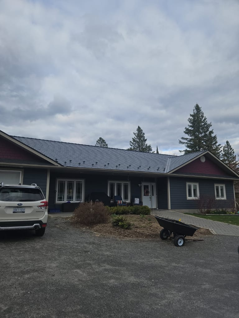 Front elevation of a single-storey ranch home in Sudbury, ON featuring Interlock deep charcoal cedar shingle aluminum metal roofing with snow guards.