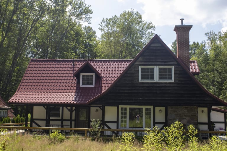 Tile Red Interlock Tile aluminum roof on a brown cottage with a red roof in a wooded area, Gravenhurst, Ontario