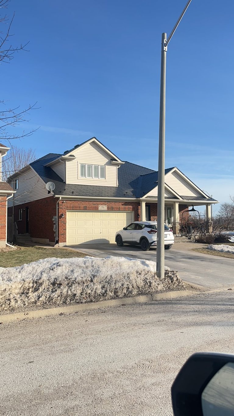 Street view of a brick single-family home in Collingwood ON with a black Interlock aluminum slate metal roof featuring multiple gable peaks and a covered porch.