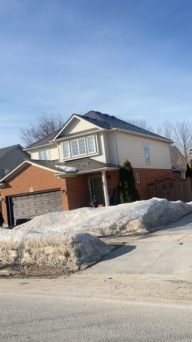 Two-storey brick home in Collingwood ON with Interlock Tudor Brown aluminum slate metal roofing on a multi-hip complex roof under clear winter sky.
