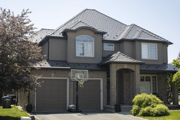Two-storey suburban home in Guelph ON with complex multi-hip Interlock Tudor Brown aluminum slate metal roofing featuring a central dormer and stone facade.