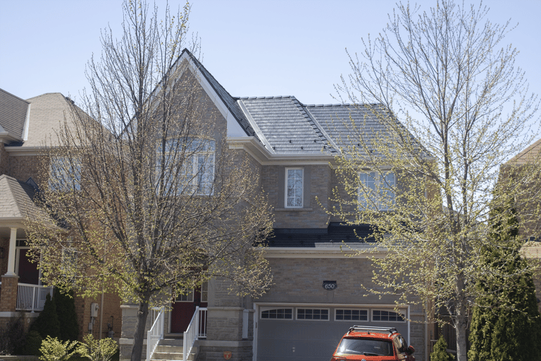Two-storey brick home in Vaughan, ON featuring a dark charcoal Interlock aluminum slate metal roof with dormers, valleys, and snow guards.