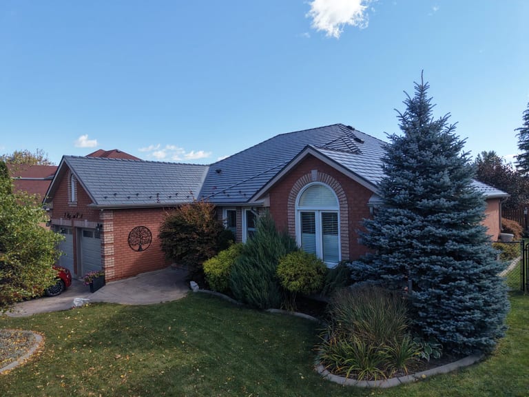 Musket Grey Interlock Cedar Shingle aluminum roof on a red ranch style home with a grey metal roof among tall, Brampton, Ontario