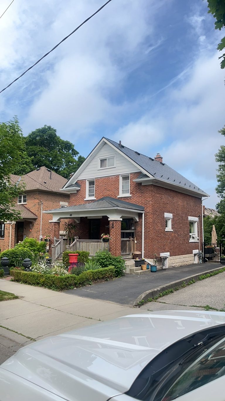 Two-storey brick Craftsman home in Kitchener ON with a steep deep charcoal Interlock aluminum slate metal roof and covered front porch.