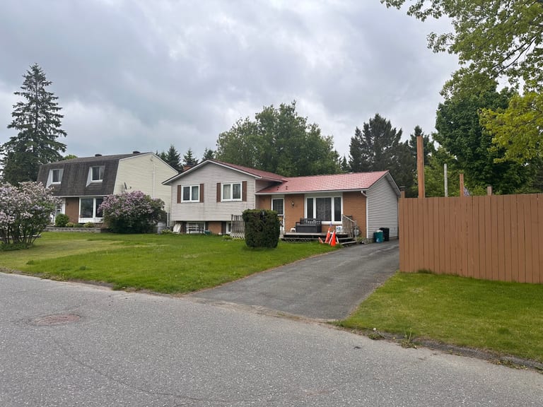 Street view of a 1.5-storey ranch-style home in Munster, ON featuring a Tile Red Interlock aluminum shingle metal roof with a simple gable profile.