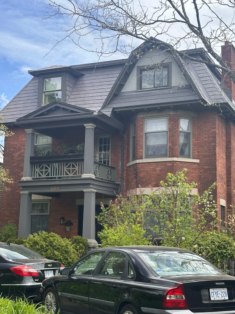 Three-storey Victorian red-brick home in Ottawa with Interlock Musket Grey aluminum slate roofing, multiple dormers, and a covered balcony entry.