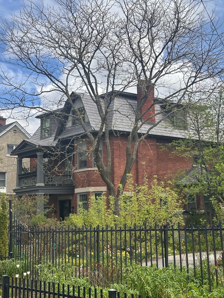 Victorian red-brick home in Ottawa with Interlock Musket Grey aluminum slate roofing, steep multi-hip profile, dormers, and chimney, viewed from street.