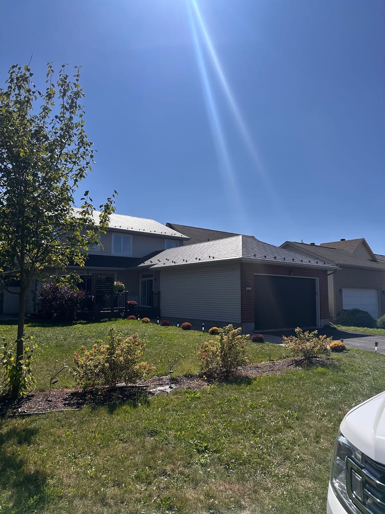 Two-storey suburban home with Interlock black aluminum slate metal roofing across multi-hip profiles, brick and vinyl siding, Ottawa ON.