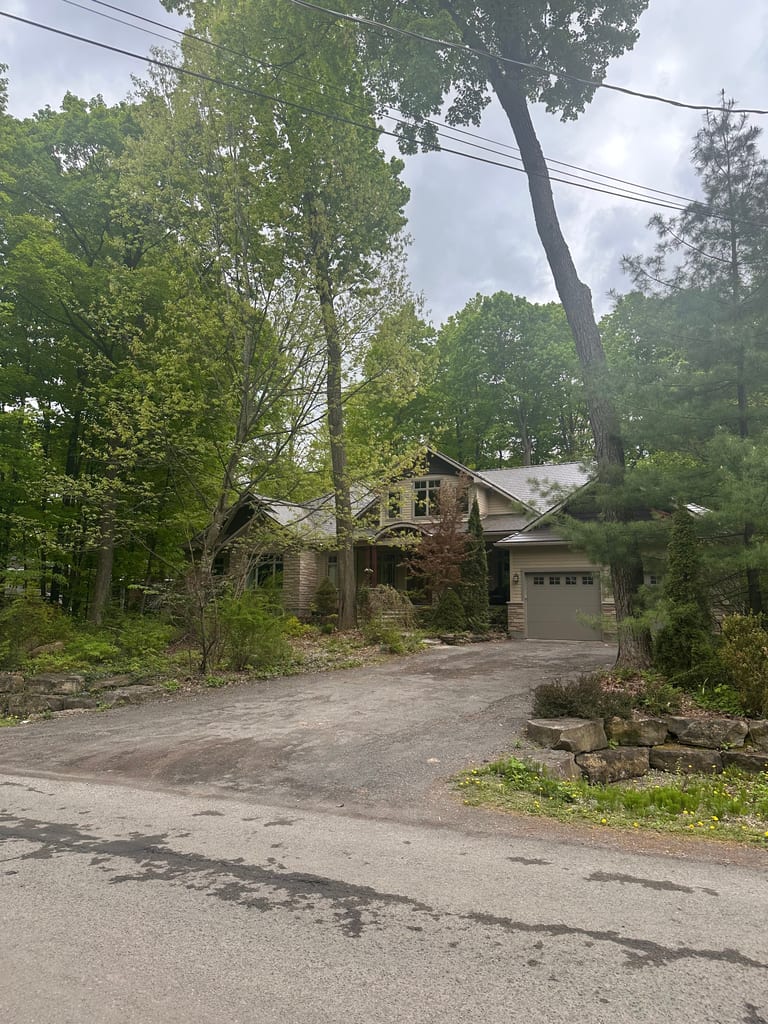 Craftsman-style home in Ottawa nestled among tall trees, featuring an Interlock Tudor Brown cedar shingle metal roof with complex multi-plane profile.