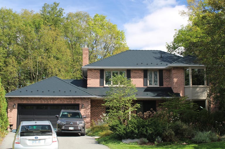 Black Interlock Slate aluminum roof on a red brick home with a black metal roof in a forested, Kingston, Ontario