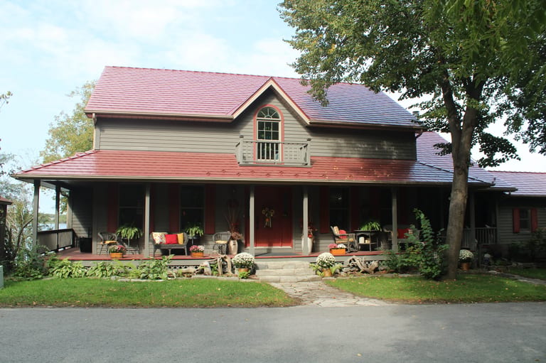 Tile Red Interlock Slate aluminum roof on a red two-storey Colonial home with dormers among tall trees, Kingston, Ontario