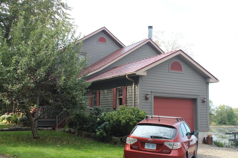 Tile Red Interlock Slate aluminum roof on a grey house with a red metal roof beside a lake, Kingston, Ontario