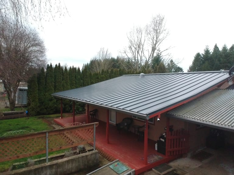 Deep Charcoal Interlock Standing Seam aluminum roof on a red single-family home with a metal roof in a forested, Scio, Oregon