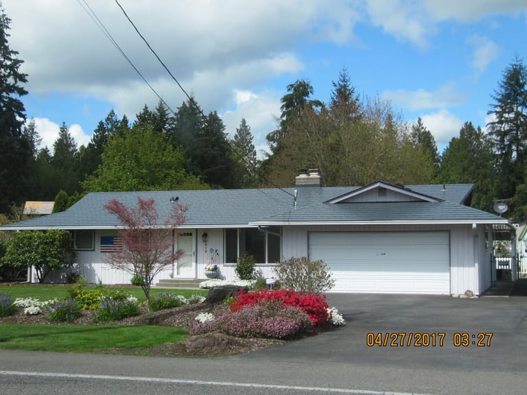 After: Deep Charcoal Interlock Slate aluminum roof on a Deep Charcoal metal roof on a white ranch home among tall, Marysville, Washington