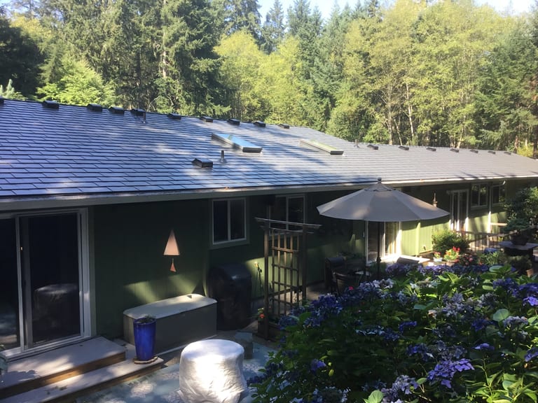 After: Deep Charcoal Interlock Slate aluminum roof on a two-storey green home with a metal roof in a forested area, Poulsbo, Washington