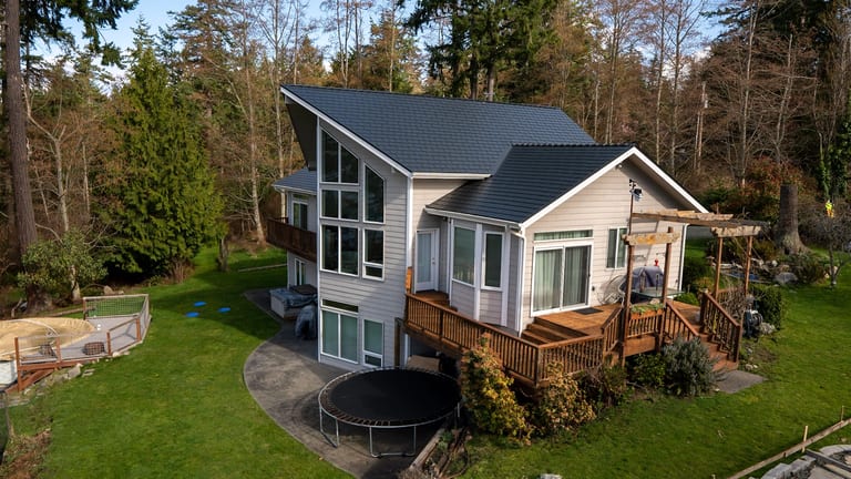 Black Interlock Slate aluminum roof on a white house with a black metal roof in a forested area, Langley, Washington