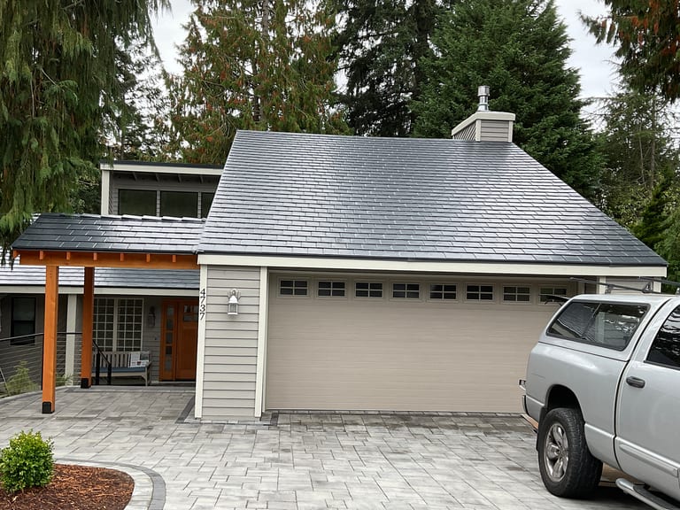 Deep charcoal Interlock aluminum slate metal roof on a Craftsman-style home in Bellevue, WA, featuring a hip roof, chimney, and covered front entry.