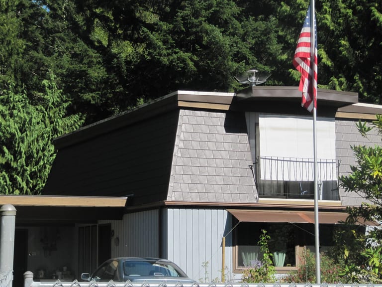 After: Tudor Brown Interlock Slate aluminum roof on a Tudor-style home with a metal roof in a forested suburban, Allyn, Washington