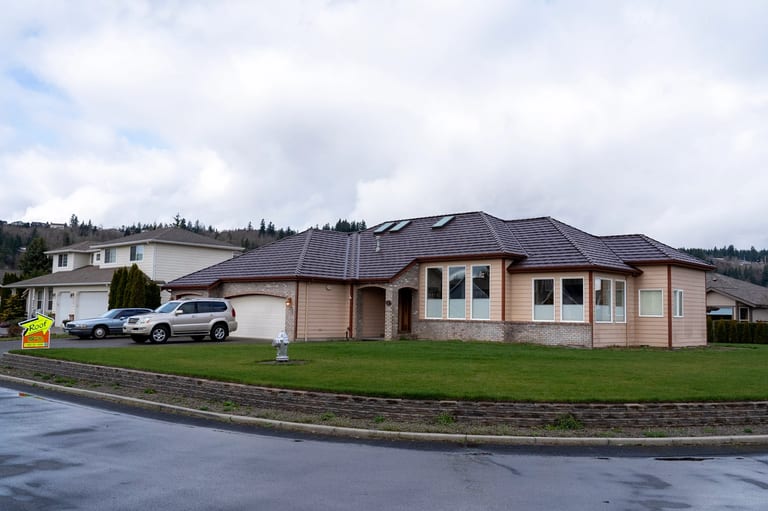 Colonial Brown Interlock Shake aluminum roof on a tan home with a brown roof among green trees, Orting, Washington