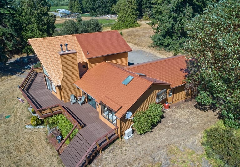 Copper Penny Interlock Cedar Shingle aluminum roof on a copper penny metal roofed chalet among tall evergreen, Sequim, Washington