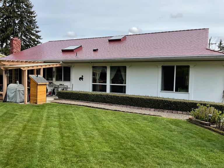 After: Tile Red Interlock Slate aluminum roof on a white one-storey home with a red metal roof in a, Lakewood, Washington