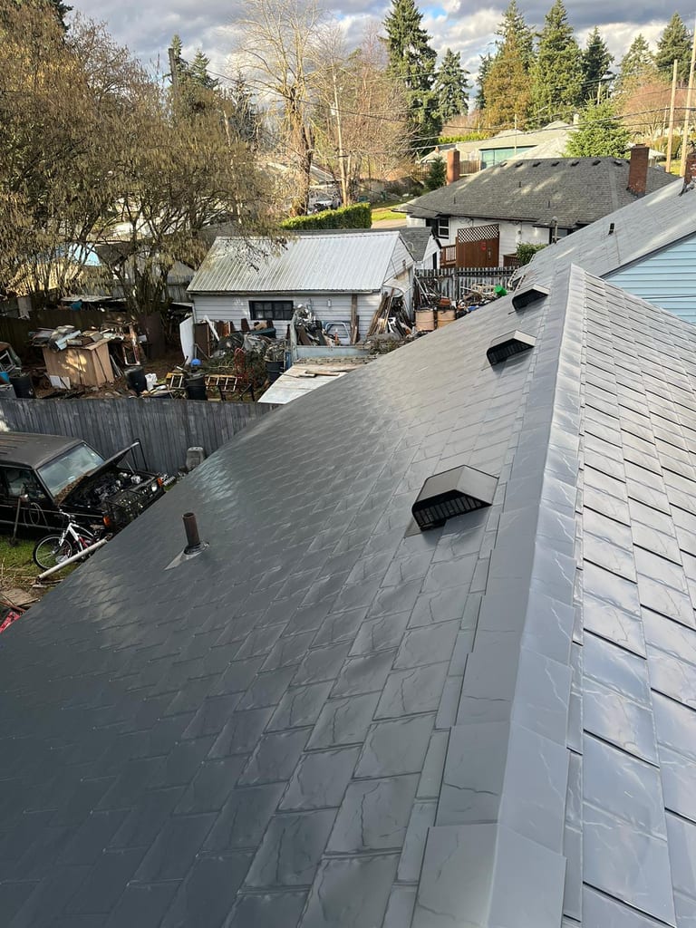 Aerial rear view of Interlock deep charcoal aluminum slate metal roof with roof louvers and vent pipe on a suburban ranch-style home in Vancouver, WA.