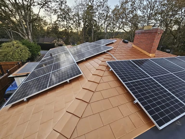 Aerial view of a Victoria, British Columbia home with two rooftop solar arrays on a Copper Penny Interlock slate aluminum roof