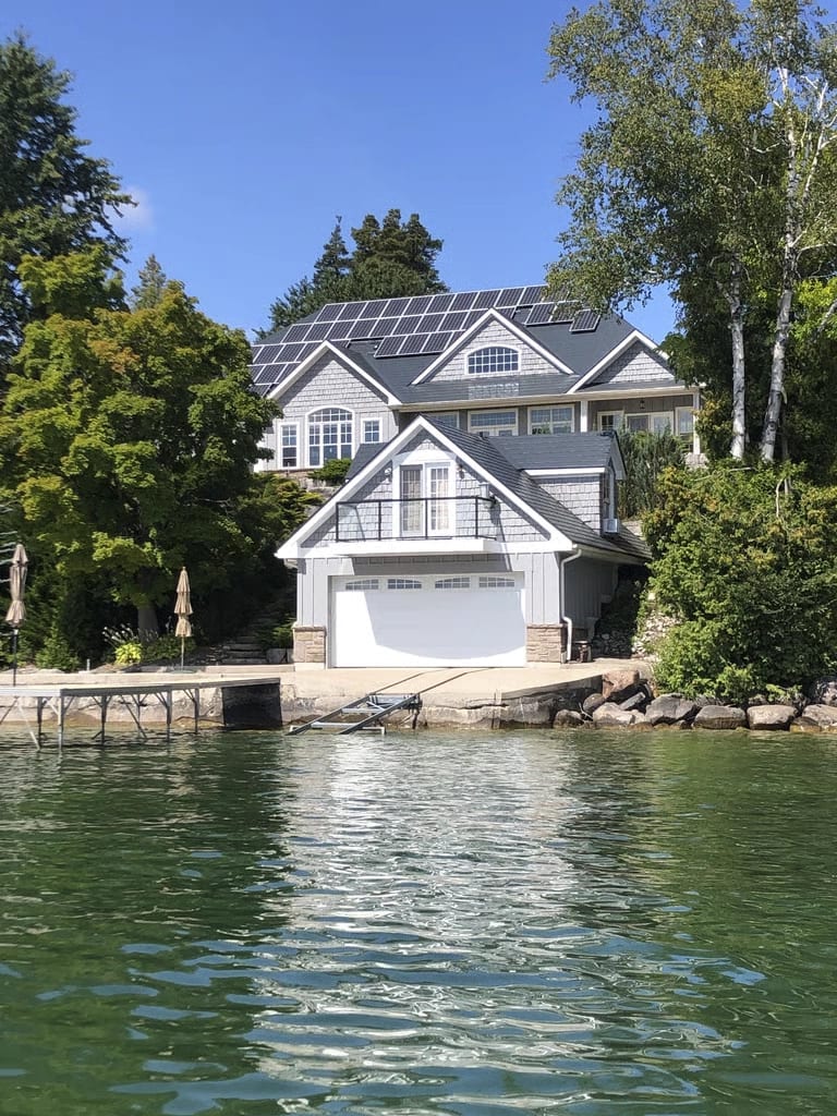 Lakefront home in Shanty Bay, Ontario with a Deep Charcoal Interlock slate aluminum roof and a full rooftop solar array, seen from the water