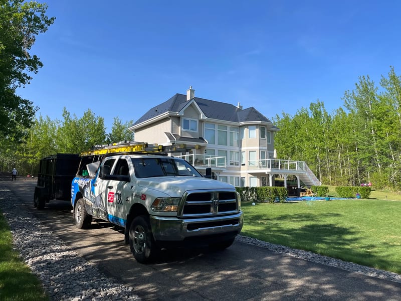 Black Interlock Cedar Shingle aluminum roof on a white two-storey home with a black metal roof in a wooded, Sherwood Park, Alberta