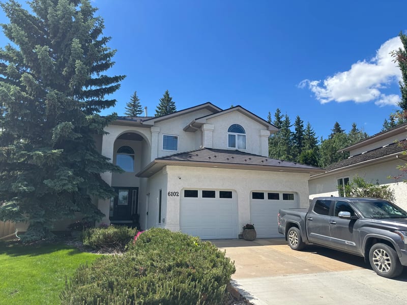 Tudor Brown Interlock Cedar Shingle aluminum roof on a Tudor style house with brown roof among tall trees, Grande Prairie, Alberta
