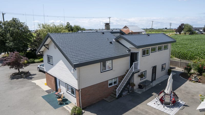 Deep Charcoal Interlock Slate aluminum roof on a two-storey home with dormers in a rural setting, Delta, British Columbia